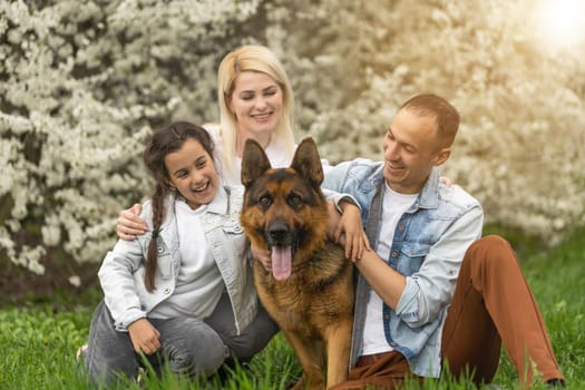 Happy family outdoors spending time together. Father, mother and daughter are having fun on a green floral grass