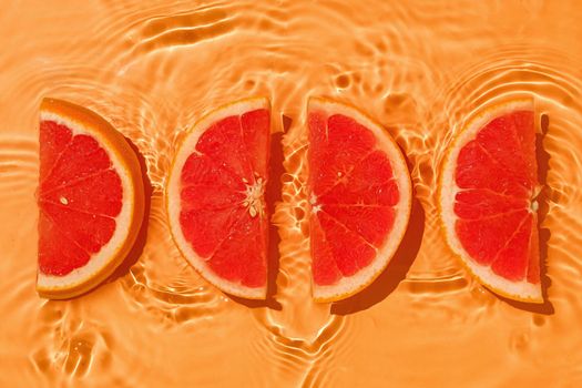 Tropical parts grapefruit fresh organic with vitamins in liquid water with wave motion. Bright concept of summer and raw food.