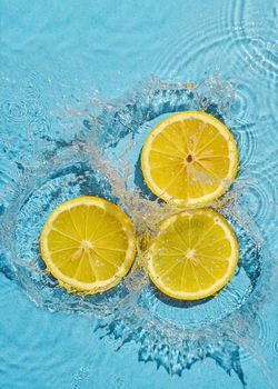 Trend contemporary concept organic juicy fresh lemon in fresh liquid water with splashes. Top view and idea of summer and health.