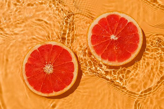 Texture summer citrus red raw fresh grapefruit with fresh water and waves. Summer minimal trend concept.