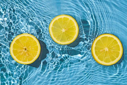 Lemon citrus tropic exotic fruit in blue transparent fresh water with motion waves. Minimal trend concept of summer and health.