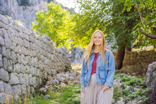 Woman tourist enjoys the view of Kotor. Montenegro. Bay of Kotor, Gulf of Kotor, Boka Kotorska and walled old city. Travel to Montenegro conceptFortifications of Kotor is on UNESCO World Heritage List since 1979.