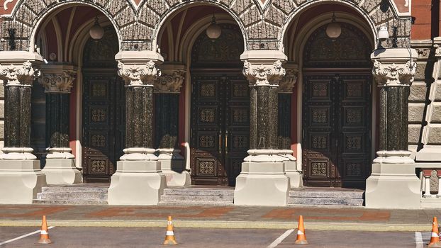 an opening, such as a door, passage, or gate, that allows access to a place. Three-door entrance with columns in a large old building.