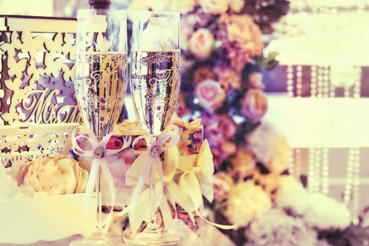 a marriage ceremony, especially considered as including the associated celebrations. Two glasses of champagne in a festive wedding decoration.