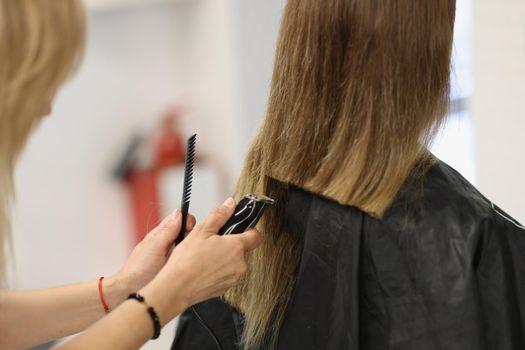 Close-up of process of hair cutting at beauty salon, using hair clipper. Beauty day, making haircut