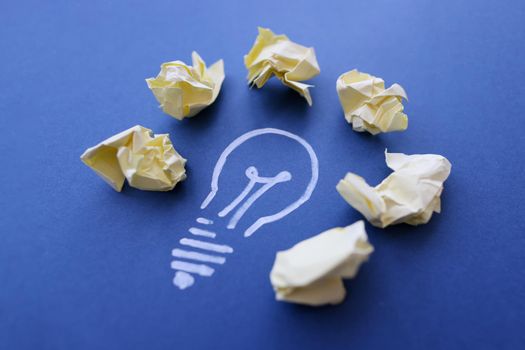 Close-up of chalk lightbulb with crumpled papers, creativity and inspiration. Creation new idea, brainstorming, innovation and business concept