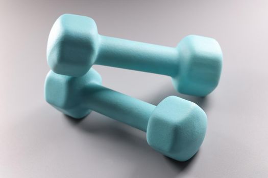 Close-up of blue dumbbells on grey background, planning weight loss, equipment for sport activity. Sport, health, physical activity, habit concept