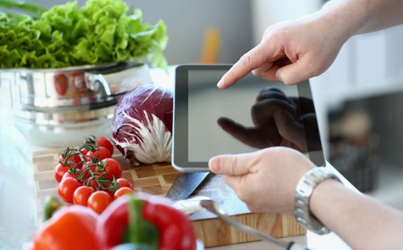 Close-up of vlogger chef showing ripe vegetables ingredients, man in apron recording tomatoes, pepper, cabbage on camera for culinary vlog. Hobby, making content concept