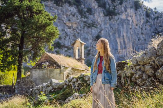 Woman tourist enjoys the view of Kotor. Montenegro. Bay of Kotor, Gulf of Kotor, Boka Kotorska and walled old city. Travel to Montenegro conceptFortifications of Kotor is on UNESCO World Heritage List since 1979.