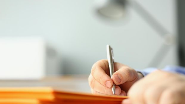 Close-up of male hand writing personal address on yellow envelope. Signing envelopes and correspondence processing. Delivery service concept