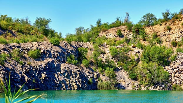 the chemical element of atomic number 86, a rare radioactive gas belonging to the noble gas series. Rocky shore of an emerald radon lake with green bushes.