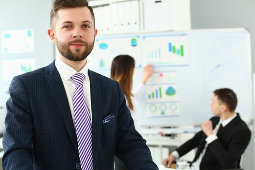 Portrait of businessman at office in presentable suit, colleagues discussing analytical data and statistics. Success, human resources, business, career growth concept