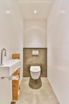 Interior of narrow restroom with sink and wall hung toilet with white walls and checkered floor