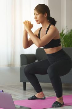 Young woman practicing yoga follow teacher in laptop online class at home. Calmness and relax concept