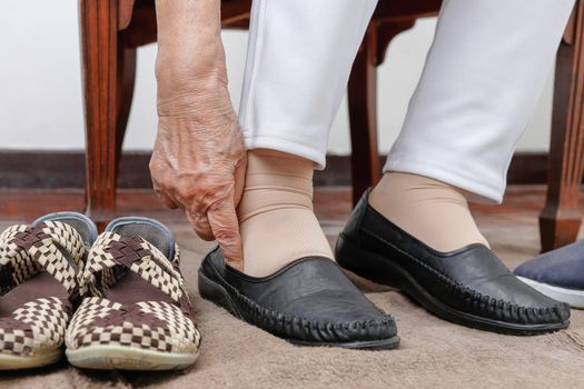 Elderly woman putting on shoes