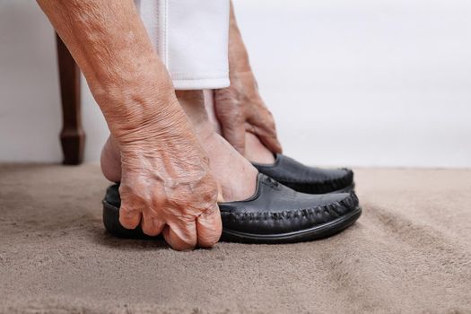 Elderly woman putting on shoes