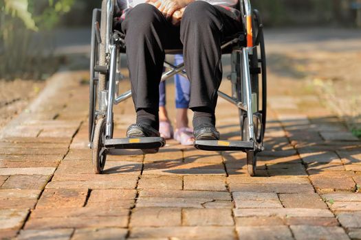 elderly woman in wheelchair walking with caregiver