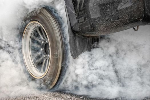 Drag racing car burns rubber off its tires in preparation for the race