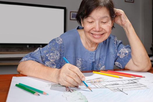 Elderly woman painting color on her drawing  , hobby at home