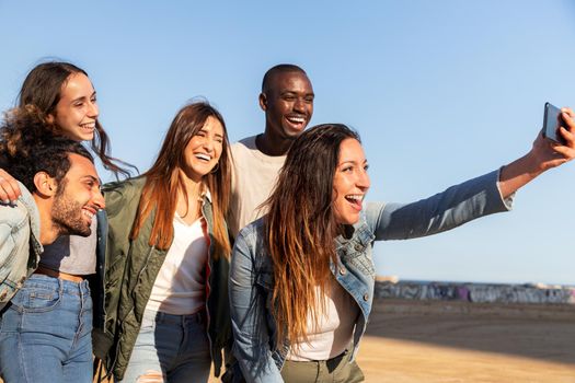 Group of happy multiracial friends taking selfie together using mobile phone. Friends having fun. Friendship, technology and social media concepts.