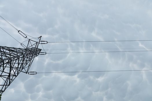 Steel pole built on a truss base to transmit high voltage against a background of storm clouds. Electricity.