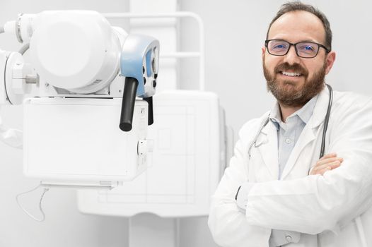 Smiling confident radiologist standing near x-ray equipment. High quality photo