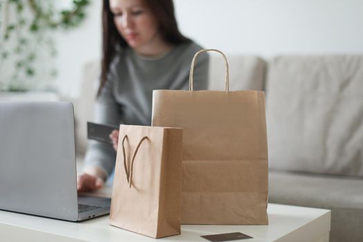 Young woman holding credit card and using laptop at home. Paying online, home shopping, internet banking, electronic store concept.