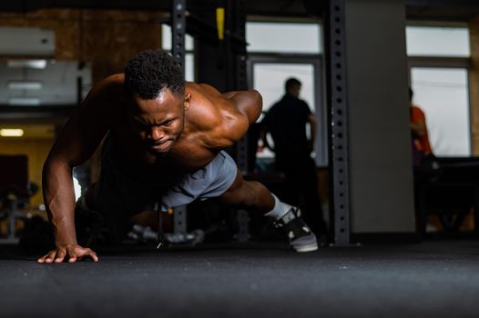 African american man doing one arm push ups in the gym