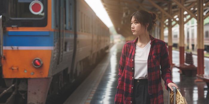 Happy Young traveler woman looking for friend planning trip at train station. Summer and travel lifestyle concept