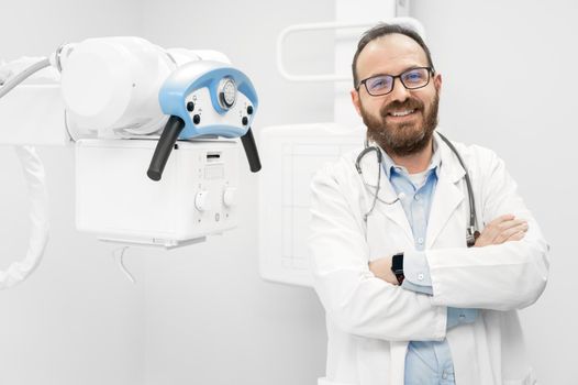 Smiling confident radiologist standing near x-ray equipment. High quality photo