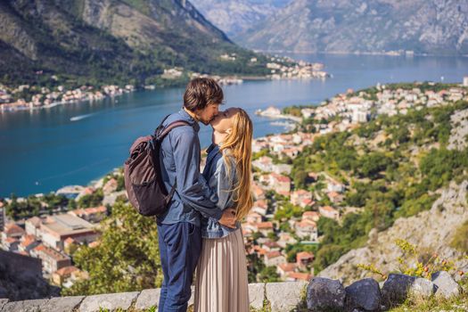 Couple woman and man tourists enjoys the view of Kotor. Montenegro. Bay of Kotor, Gulf of Kotor, Boka Kotorska and walled old city. Travel to Montenegro concept. Fortifications of Kotor is on UNESCO World Heritage List since 1979.