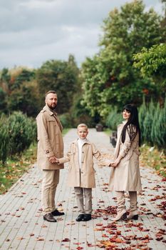 A happy family is walking in the park. Mom, dad and son are chatting and walking. A stylish family. parents in love