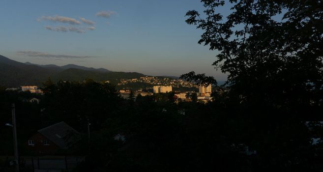 LAZAREVSKOE, SOCHI, RUSSIA - MAY, 27, 2021: Panorama of sunset in the mountains. A magical view of the sea and small town from the observation deck.