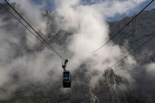 Foggy landscape showing a cable car and a rocky mountain in Fuente De in Picos de Europa in Spain