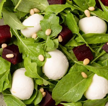 Healthy eating. Beetroot, mozzarella and arugula salad with pine nuts top view