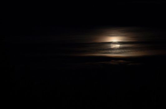 Full moon behind some clouds in a dark night