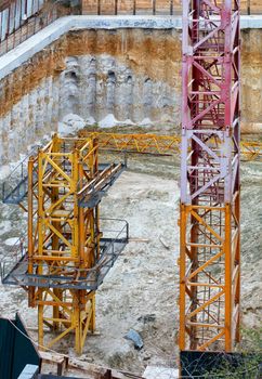 The tower crane components are laid out around the perimeter of the construction site for further assembly and installation, vertical image.