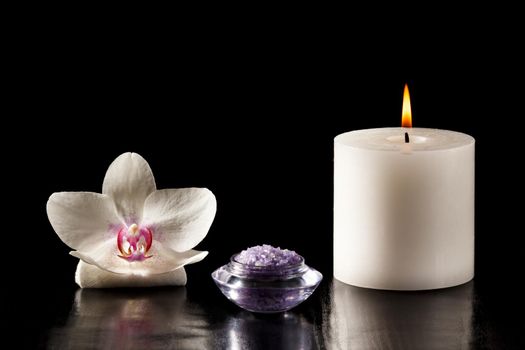 White orchid flower, bowl with sea salt for spa, candle on black background