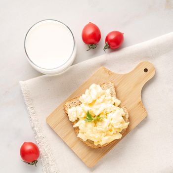 Sandwich with pan-fried scrambled eggs on a wooden cutting board, top view.