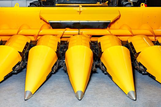 Front of sharp cones of yellow corn harvester, close-up.