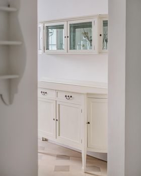 Classic wooden buffet cabinet for kitchenware in bright home interior. Storage furniture. View from hallway