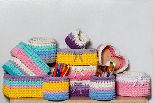 Multi-colored wicker textile baskets of rectangular and round shape for storing women's cosmetics and jewelry, close-up, copy space.
