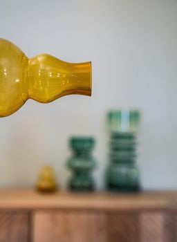 Bottleneck of yellow transparent bottle with few vases at the blurred background. Interior decoration