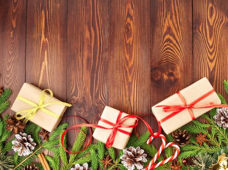 Christmas and Happy New Year dark brown background. Gift Christmas box, fir branches, a wooden table, top view, copy space