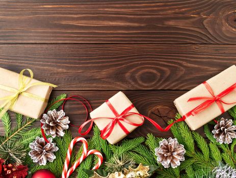 Christmas and Happy New Year dark brown background. Gift Christmas box, fir branches, a wooden table, top view, copy space