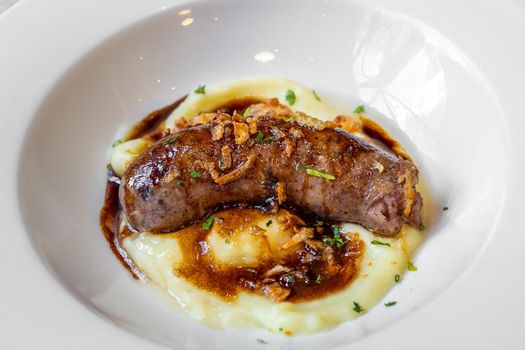 Botifarra - catalonian traditional dish served with potato puree and sauce. Barbecued spanish pork meat sausage