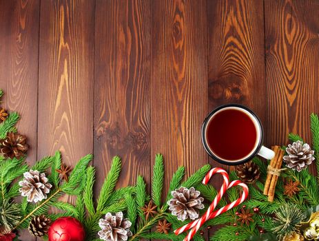 Christmas and Happy New Year background with tea. Top view, copy space. Fir branches, a brown dark wooden table