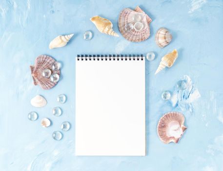 Mock up with frame of seashell and notepad on blue stone background, scallop shell, copy space. Summer concept of holiday by sea