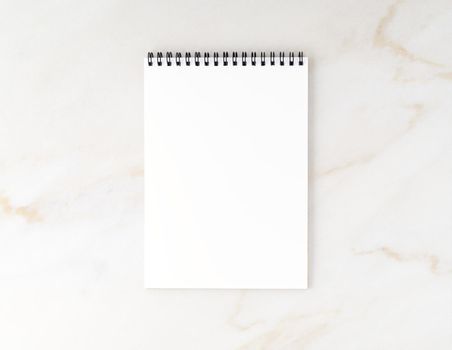 Top view of beige marble desktop with a notepad. Mock up, empty space