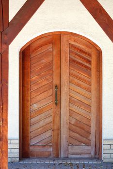 Entrance wooden doors of an old Ukrainian village hut with a massive brass handle and slanting even planks.